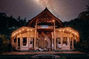 Photo of a bamboo house at night with a stary sky
